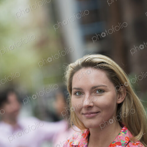 City life in spring. A woman with long blonde hair looking at the camera.