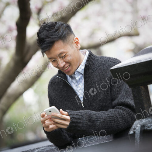 City life in spring. A young man outdoors in a city park. Sitting on a bench. City life in spring. A young man outdoors in a city park. Sitting on a bench.