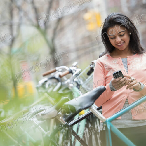 City life in spring. A young woman in a peach coloured shirt, using her smart phone.… City life in spring. A young woman in a peach coloured shirt, using her smart phone.…