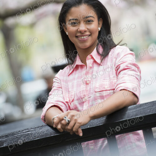 City life in spring. A young woman with black hair, wearing a pink shirt, looking over…