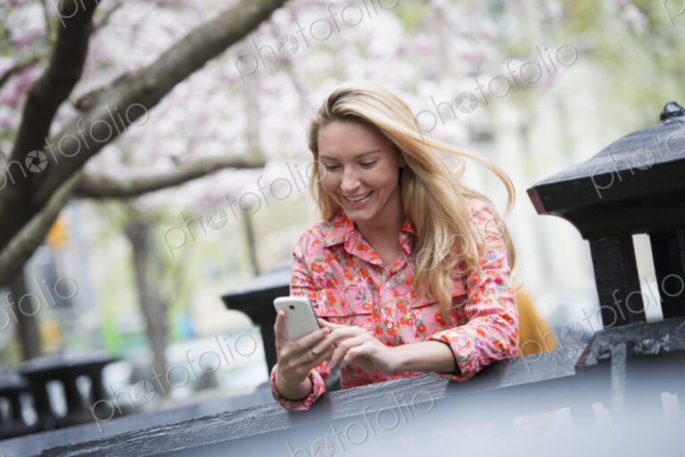 City life in spring. A young woman with long blonde hair sitting in a city park,…