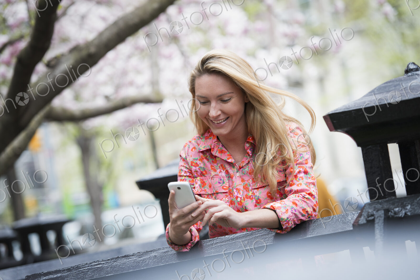 City life in spring. A young woman with long blonde hair sitting in a city park,…
