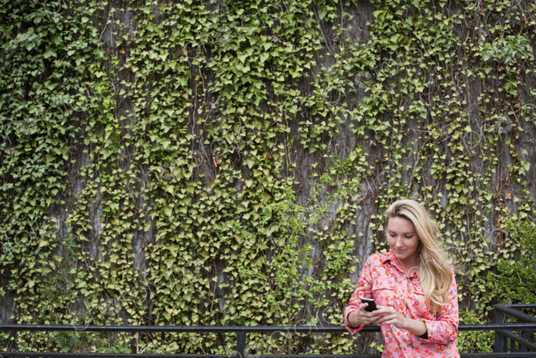 City life in spring. City park with a wall covered in climbing plants and ivy. A young…