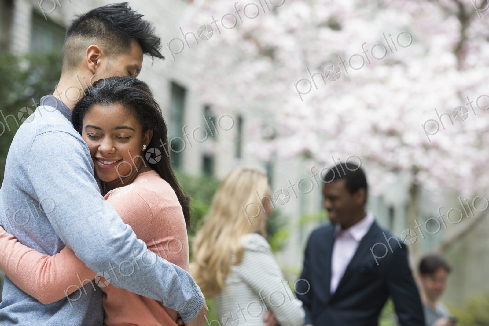 City life in spring. Young people outdoors in a city park. A couple embracing, and two…