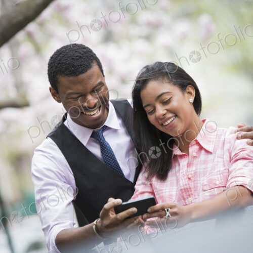 City life in spring. Young people outdoors in a city park. A couple side by side, with…