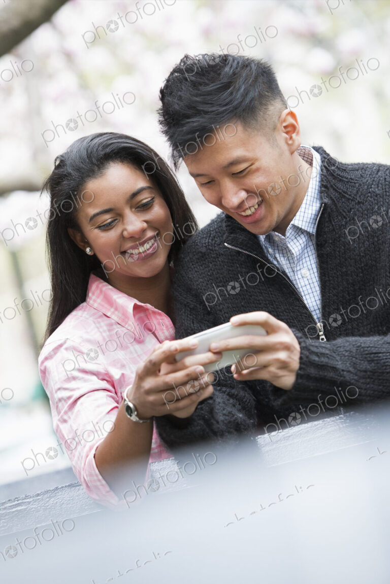 City life in spring. Young people outdoors in a city park. A couple side by side,…