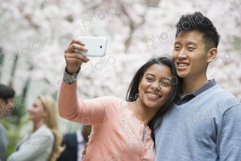 City life in spring. Young people outdoors in a city park. A couple taking a self…