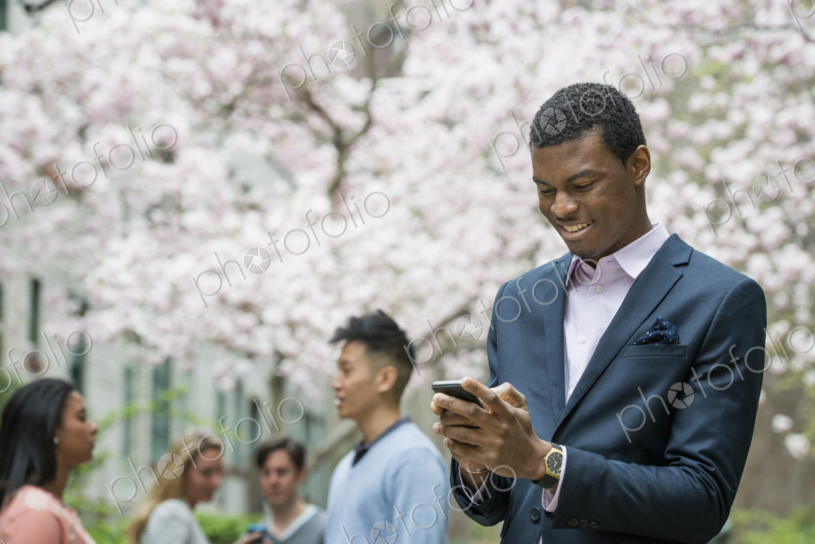 City life in spring. Young people outdoors in a city park. A man checking his cell…