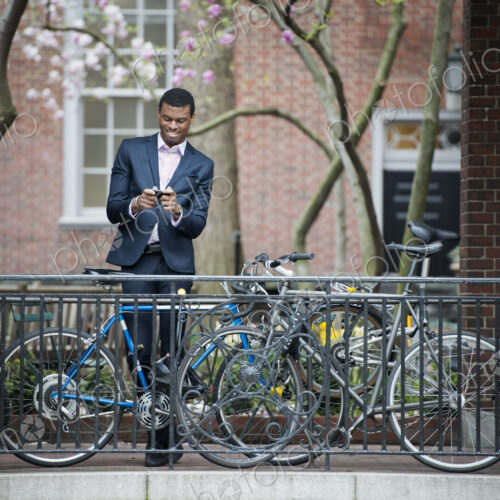 City life in spring. Young people outdoors in a city park. A man in a suit, beside a… City life in spring. Young people outdoors in a city park. A man in a suit, beside a…