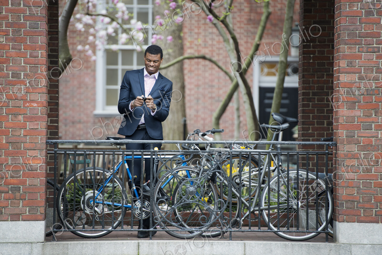 City life in spring. Young people outdoors in a city park. A man in a suit, beside a…