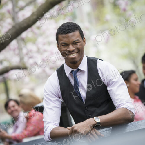 City life in spring. Young people outdoors in a city park. A man sitting down, with…