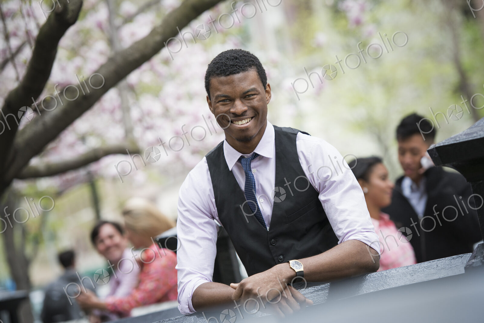 City life in spring. Young people outdoors in a city park. A man sitting down, with…