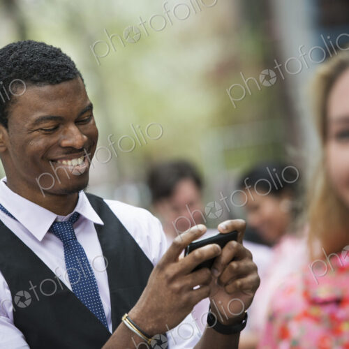 City life in spring. Young people outdoors in a city park. A man smiling as he looks…