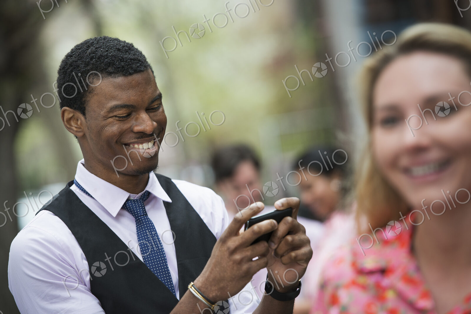 City life in spring. Young people outdoors in a city park. A man smiling as he looks…