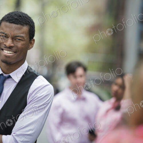City life in spring. Young people outdoors in a city park. A man with arms folded…