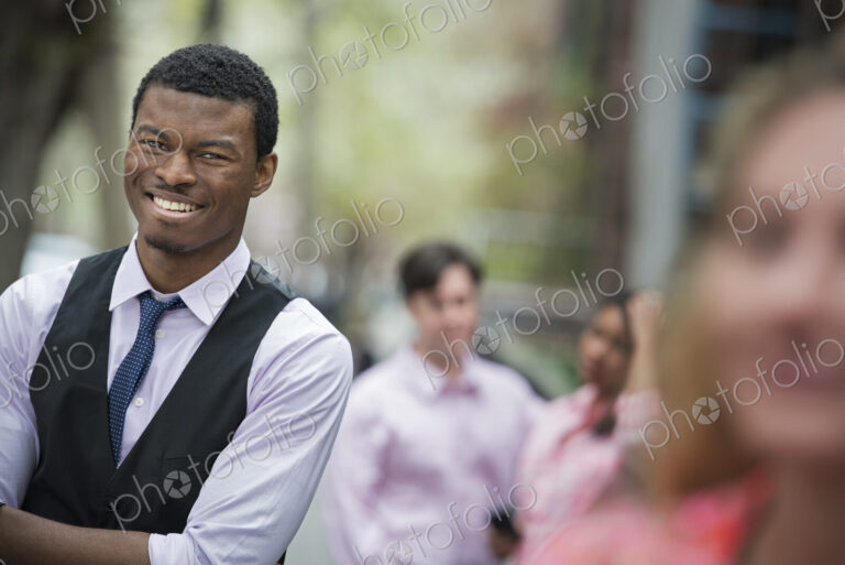 City life in spring. Young people outdoors in a city park. A man with arms folded…