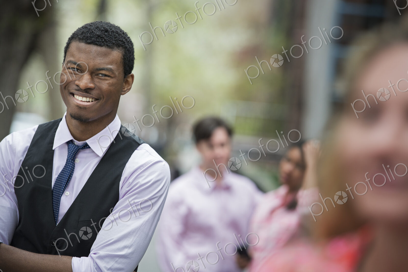 City life in spring. Young people outdoors in a city park. A man with arms folded…
