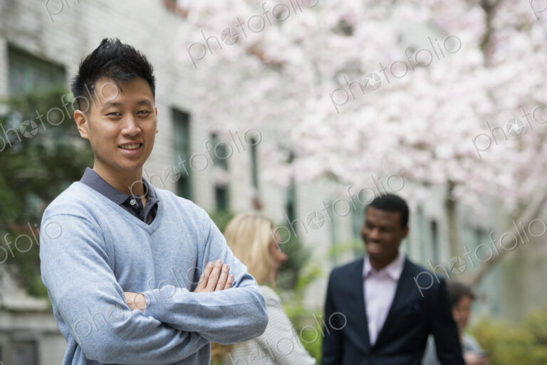 City life in spring. Young people outdoors in a city park. A man with his arms folded…