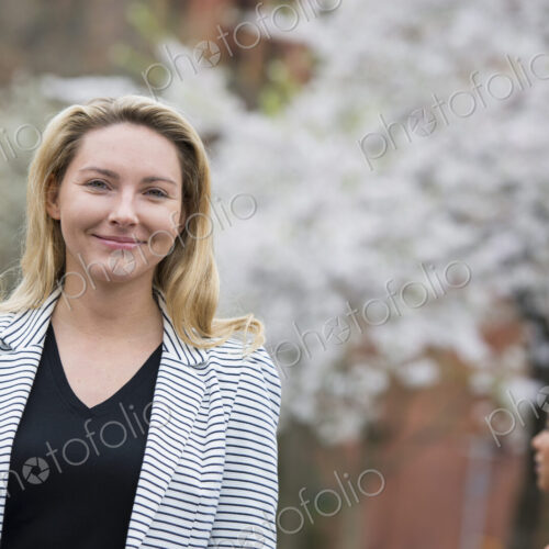 City life in spring. Young people outdoors in a city park. A woman in a grey jacket… City life in spring. Young people outdoors in a city park. A woman in a grey jacket…