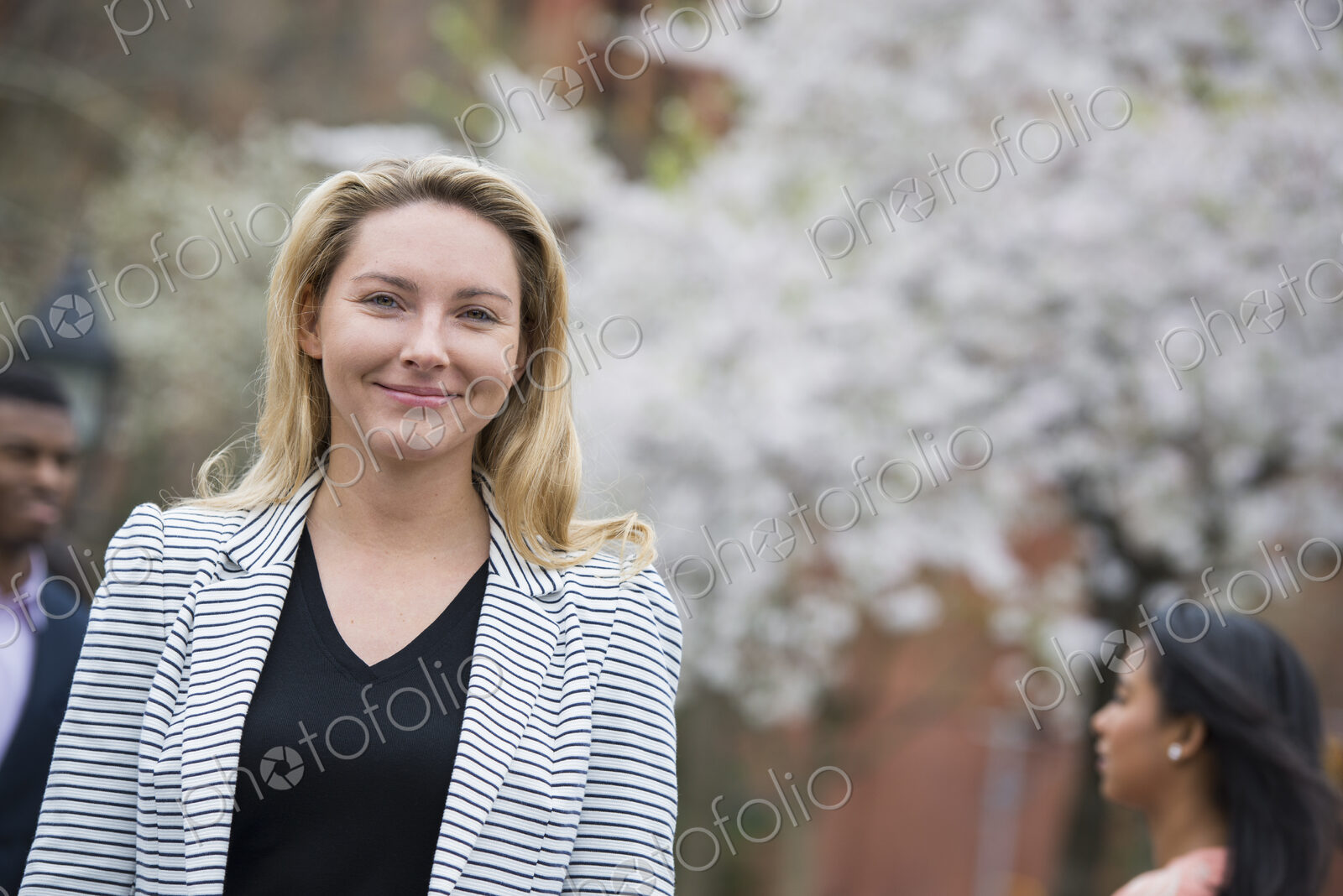 City life in spring. Young people outdoors in a city park. A woman in a grey jacket…