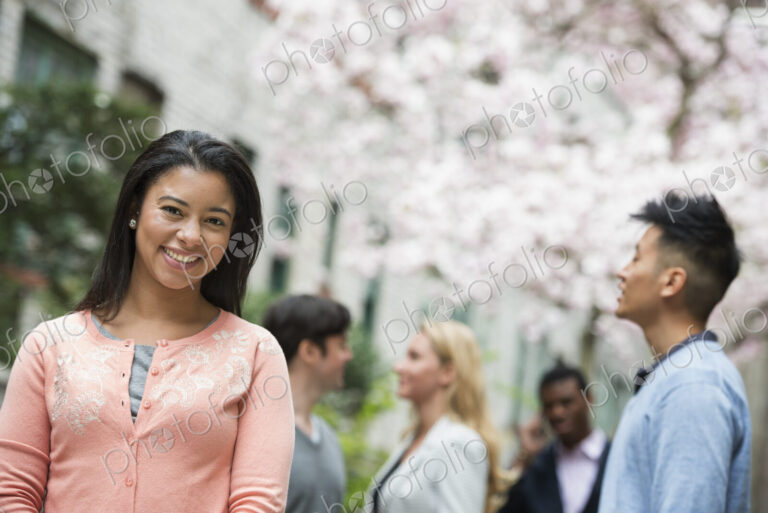 City life in spring. Young people outdoors in a city park. A woman in a pink shirt…