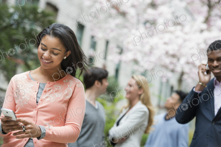 City life in spring. Young people outdoors in a city park. A woman in a pink shirt…