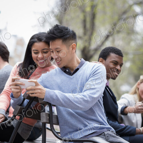 City life in spring. Young people outdoors in a city park. Sitting on a bench. A man… City life in spring. Young people outdoors in a city park. Sitting on a bench. A man…