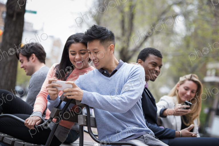 City life in spring. Young people outdoors in a city park. Sitting on a bench. A man…