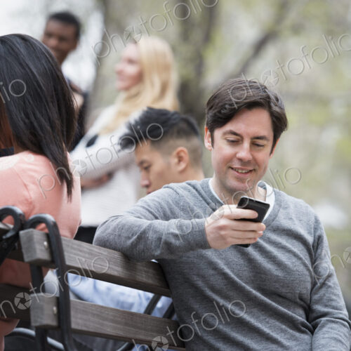 City life in spring. Young people outdoors in a city park. Sitting on a park bench.… City life in spring. Young people outdoors in a city park. Sitting on a park bench.…