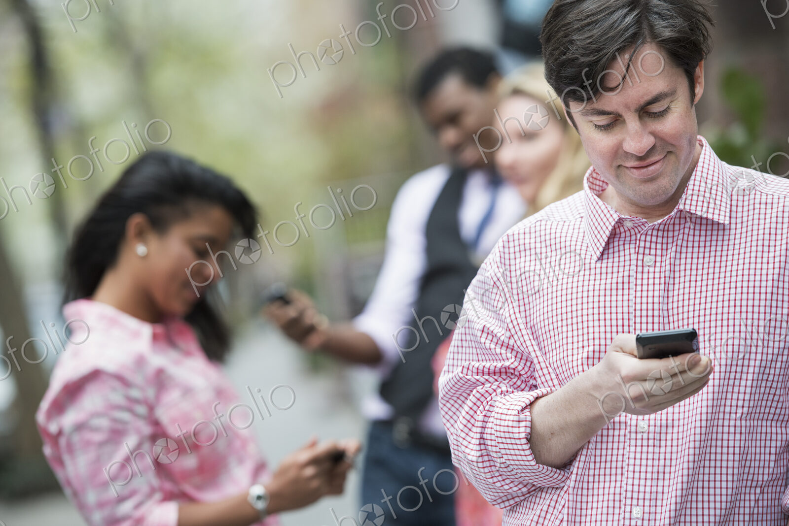 City life in spring. Young people outdoors in a city park. Three people checking,…