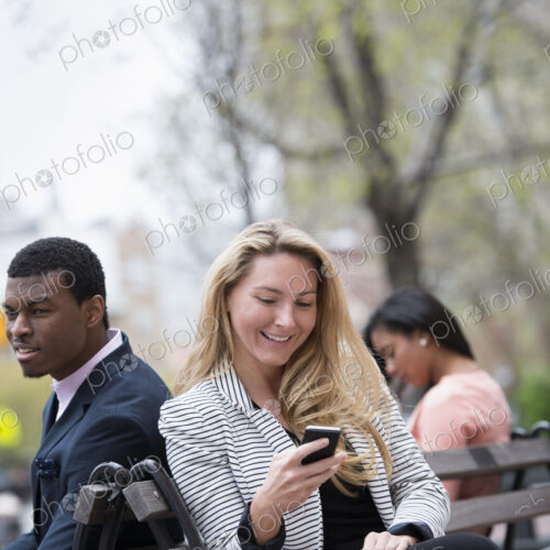 City life in spring. Young people outdoors in a city park. Three people sitting on a…