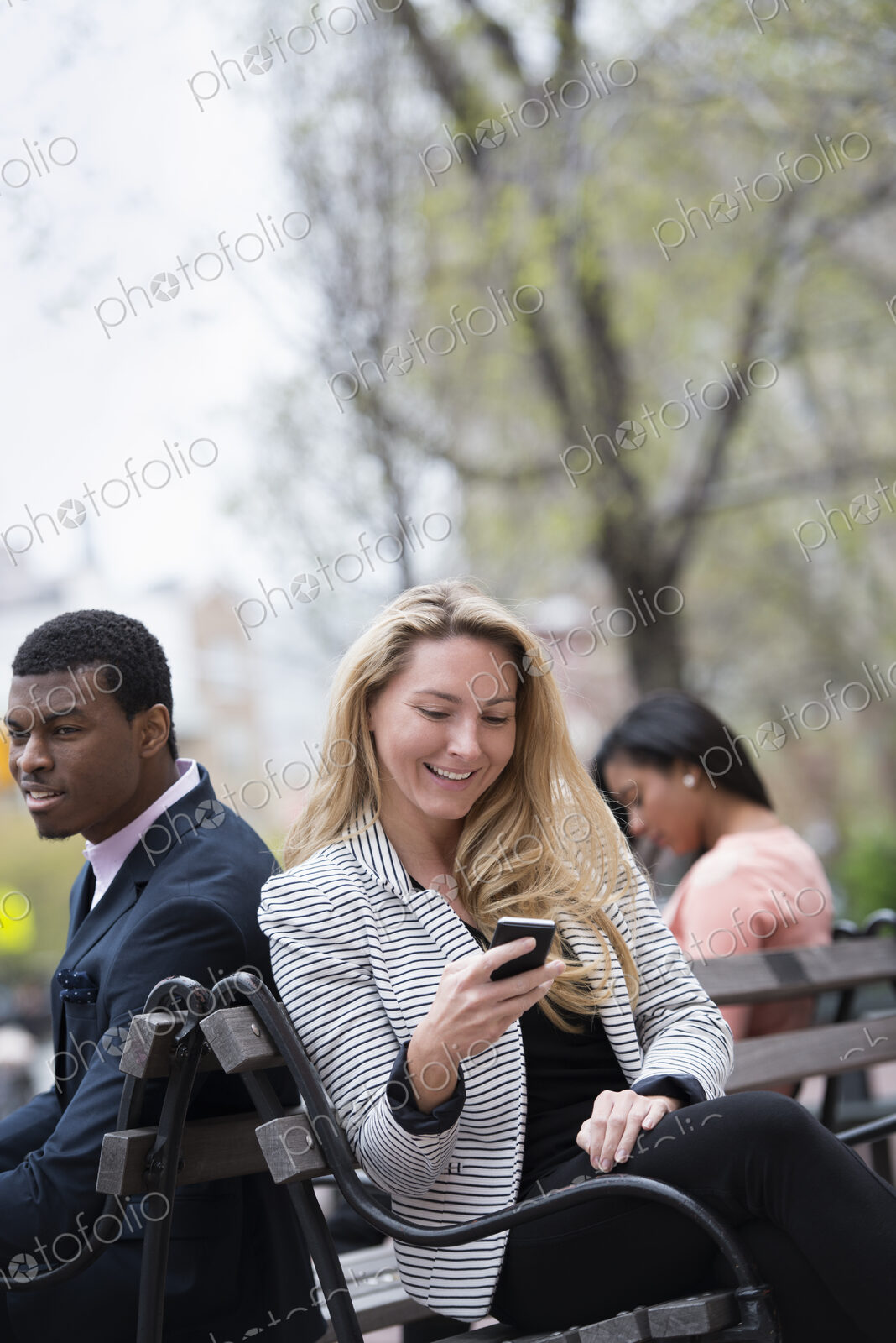 City life in spring. Young people outdoors in a city park. Three people sitting on a…