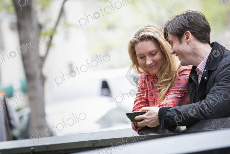 City life in spring. Young people outdoors in a city park. Two people sitting side by…