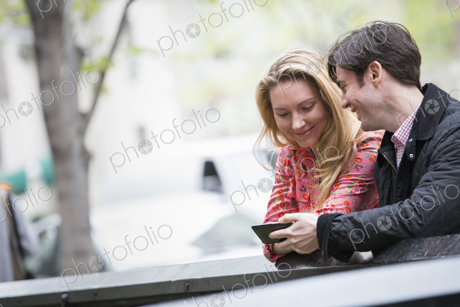 City life in spring. Young people outdoors in a city park. Two people sitting side by…