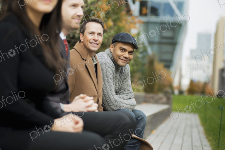 City life. A group of people on the go, keeping in contact, sitting on a bench. Men…