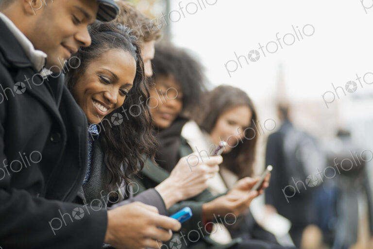 City life. A group of people on the go, keeping in contact, using mobile phones. Men…