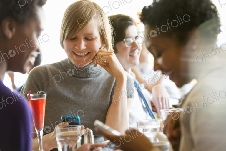 City life. A group of people sitting in a cafe or bar around a table. Men and women…
