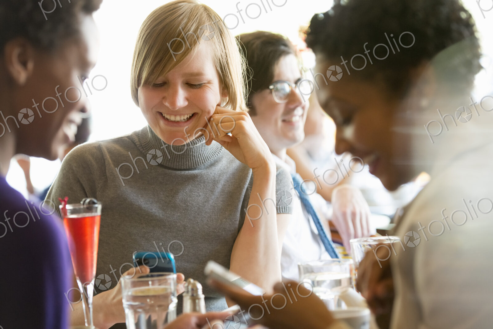 City life. A group of people sitting in a cafe or bar around a table. Men and women…
