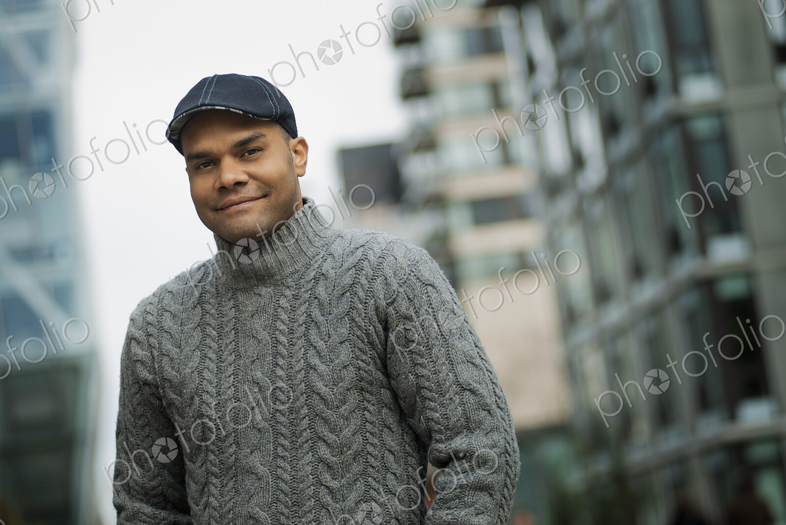 City life. A man in a flat hat, and jumper on the street of a city.