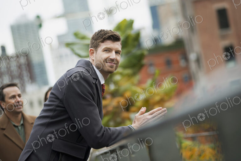 City life. A man in a winter coat leaning on a railing, taking time out. City…
