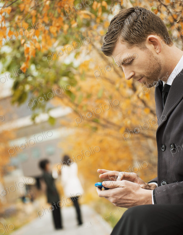 City life. A man in the park checking and texting, keeping in contact, using a mobile…