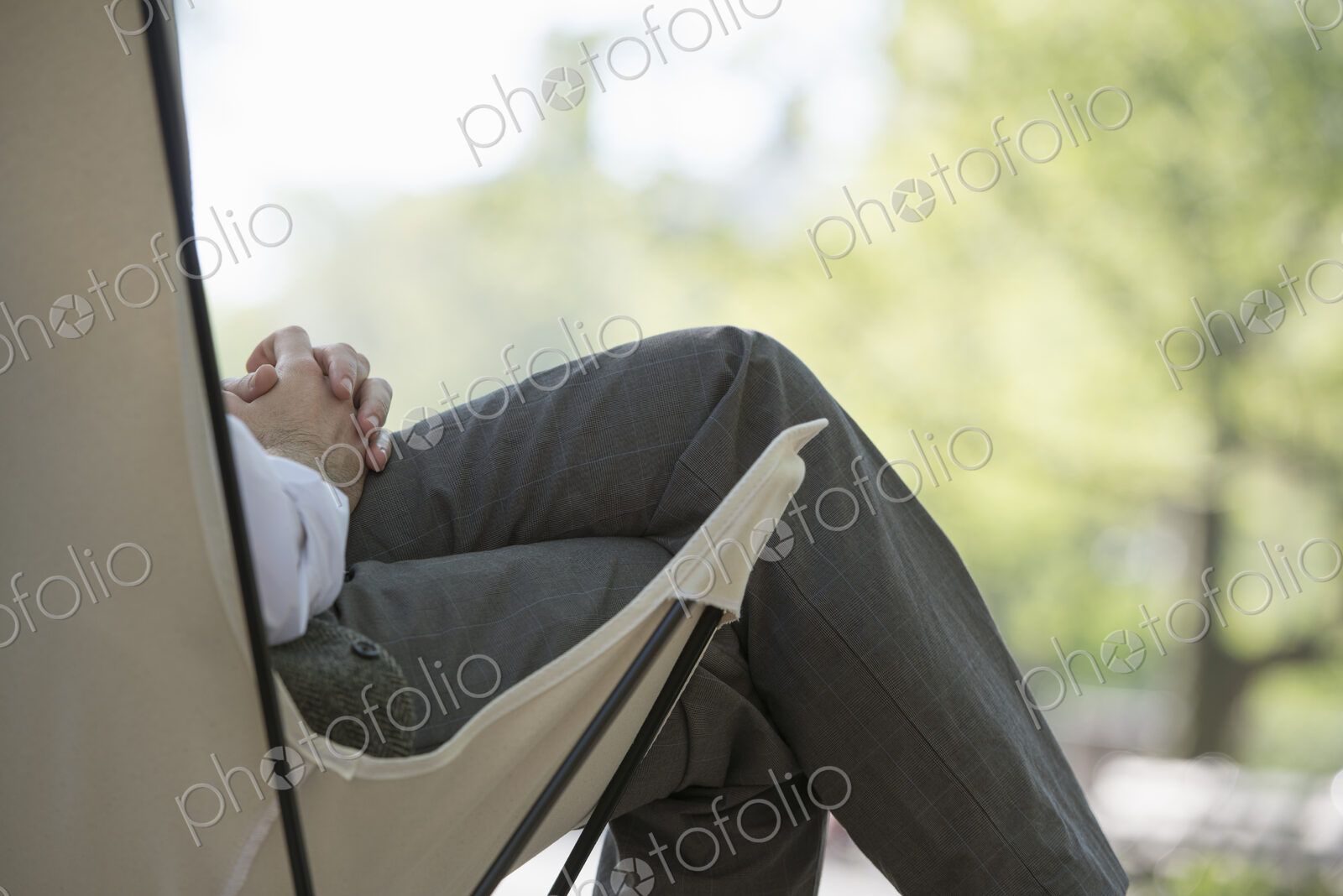 City life. A man sitting in a canvas camping chair in the park.