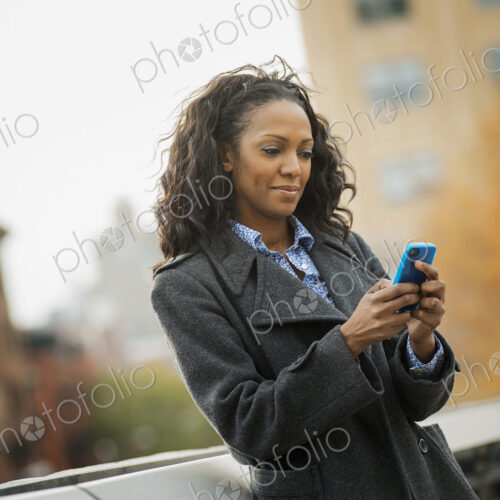 City life. A woman in a coat, checking and texting, keeping in contact, using a mobile…