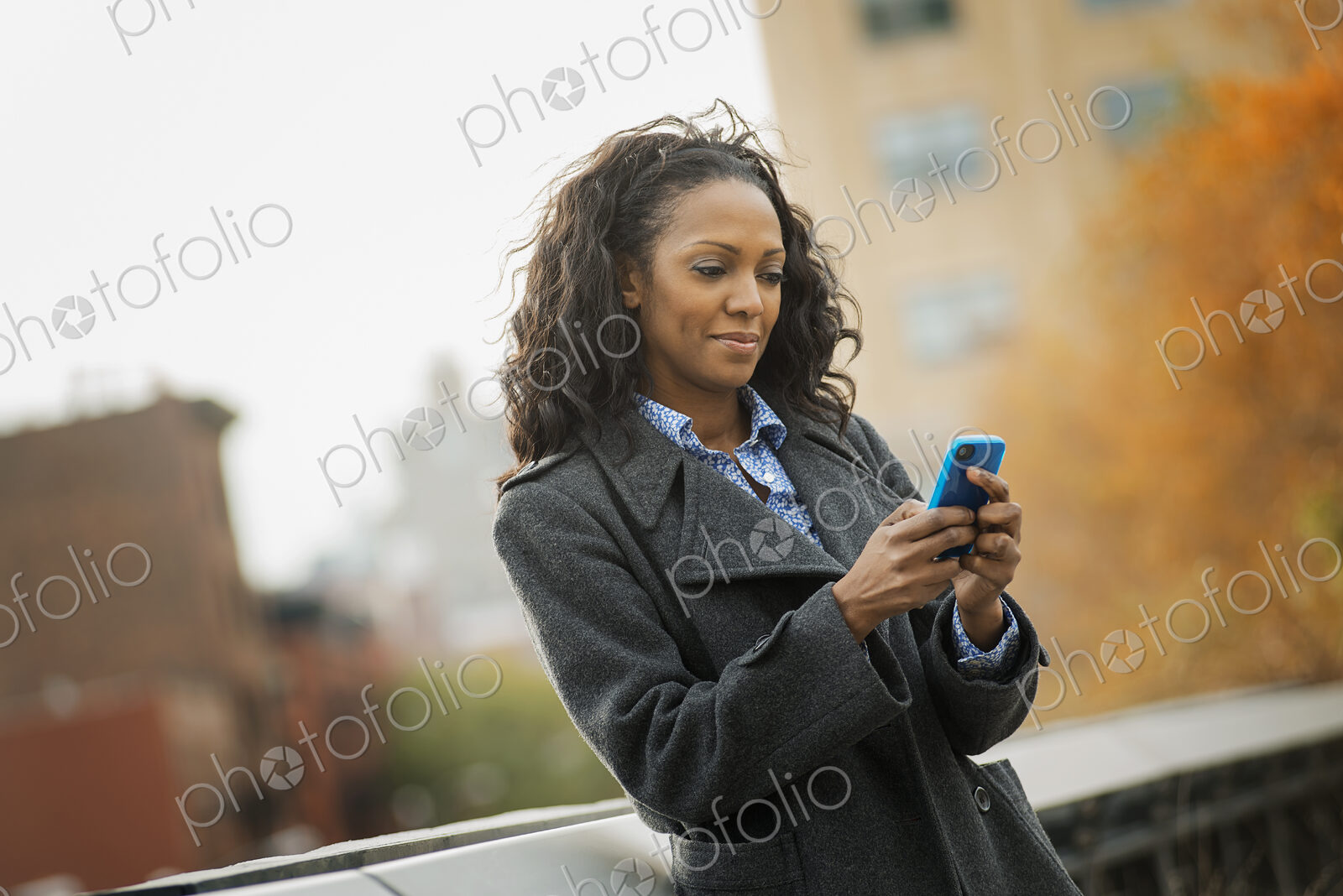 City life. A woman in a coat, checking and texting, keeping in contact, using a mobile…