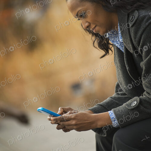 City life. A woman in a coat, checking and texting, keeping in contact, using a mobile…