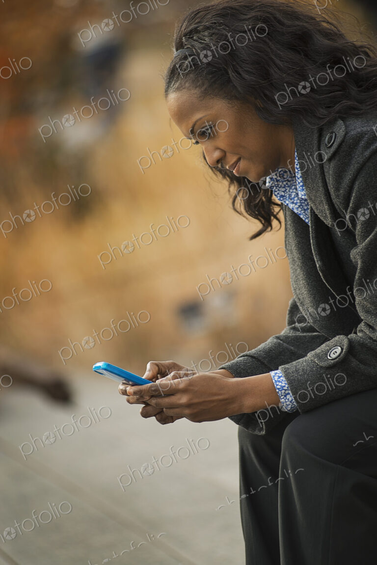 City life. A woman in a coat, checking and texting, keeping in contact, using a mobile…