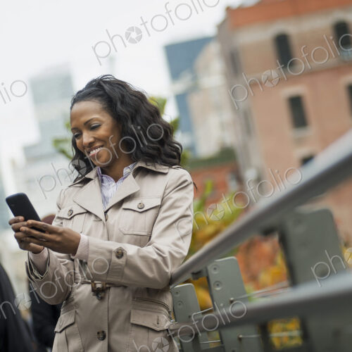 City life. A woman in a coat, checking and texting, keeping in contact, using a mobile… City life. A woman in a coat, checking and texting, keeping in contact, using a mobile…