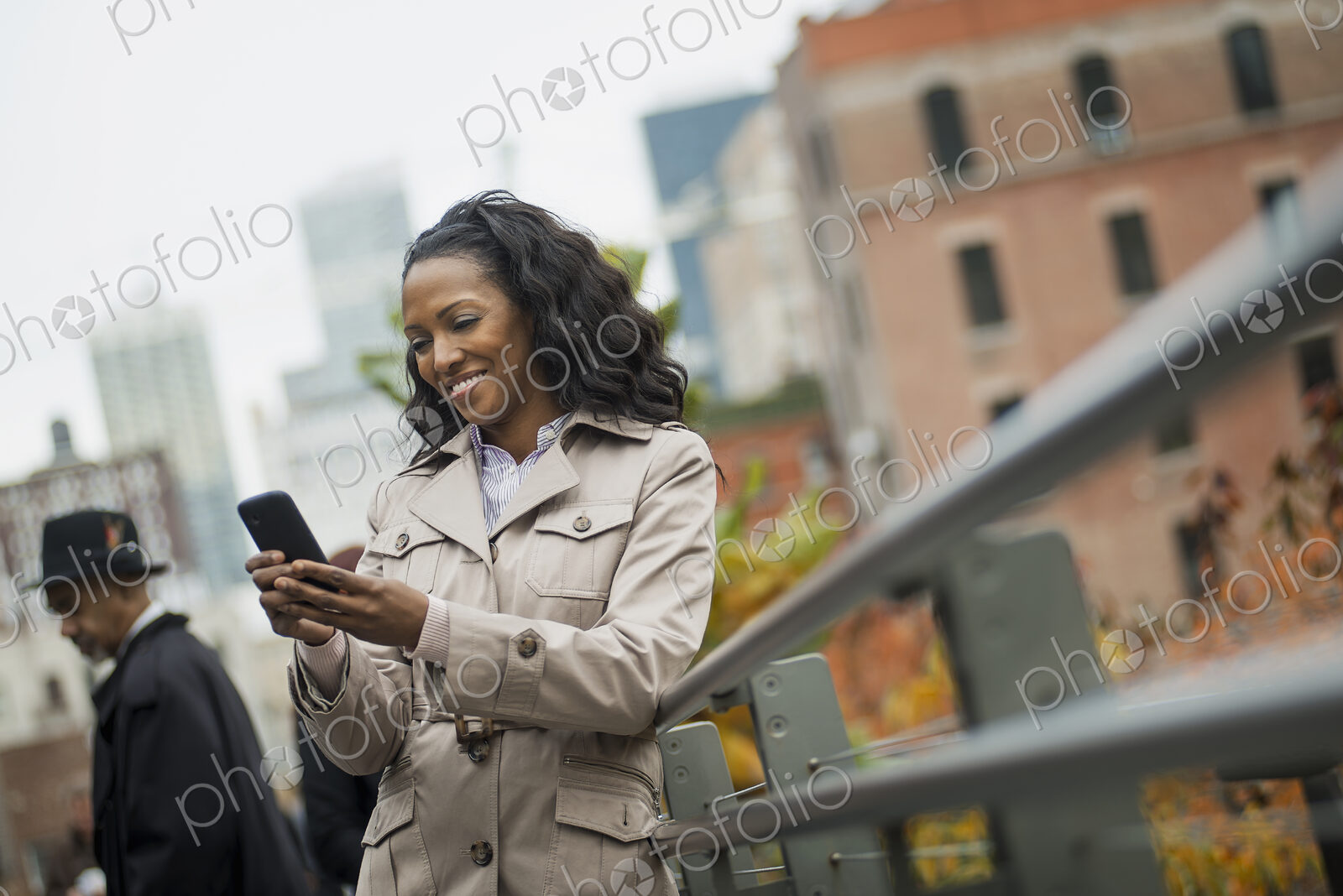 City life. A woman in a coat, checking and texting, keeping in contact, using a mobile…