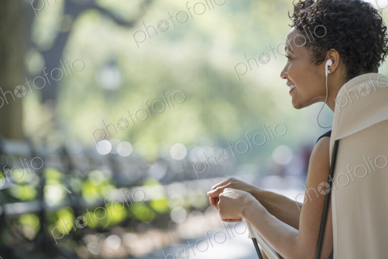 City life. A woman sitting in a camping chair in a city park.