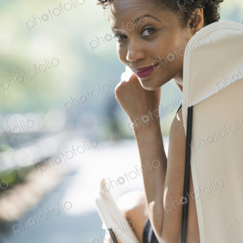 City life. A woman sitting in a camping chair in a city park, smiling and looking over…